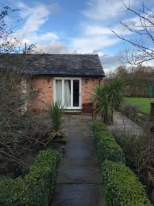 a small brick house with a window and a walkway at Moss Farm B&B in Knutsford