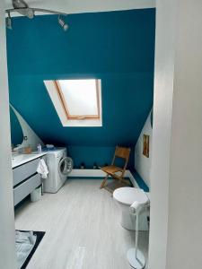 een blauwe badkamer met een toilet en een raam bij Maison de village chez Josy in Coudun