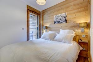 een slaapkamer met een wit bed en een houten muur bij Carlina 101 in Morzine