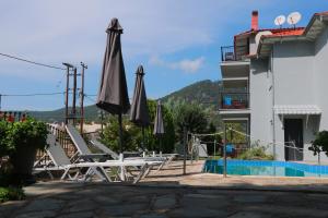 a group of chairs and umbrellas next to a pool at Aliston Hotel Studios, Adults Only in Skala Potamias