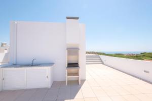 a white kitchen with a sink and a view of the ocean at Penthouse with rooftop pool - Duna Parque Group in Vila Nova de Milfontes