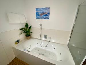 a white bath tub with a plant in a bathroom at Luxus Penthouse Bregenz Feldmoos mit Whirlpool & riesen Terrasse, nahe Festspiele in Bregenz