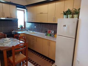 a kitchen with a white refrigerator and a table at Geni Apartment in Korçë
