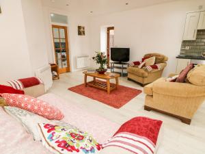 a living room with a couch and chairs and a tv at May's Cottage in Bushmills
