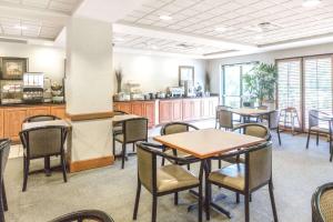 a dining room with tables and chairs and a kitchen at Wingate by Wyndham Tupelo in Tupelo