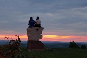two people sitting on top of a stone statue at sunset at Limerhof in Waischenfeld