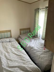 two beds sitting next to each other in a bedroom at Summer Breeze Deluxe Caravan Rental in Saint Osyth