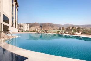 a swimming pool with chairs and mountains in the background at Ramada Iskenderun in İskenderun