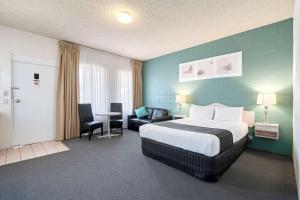 a hotel room with a bed and a table and chairs at Comfort Inn & Suites King Avenue in Sale