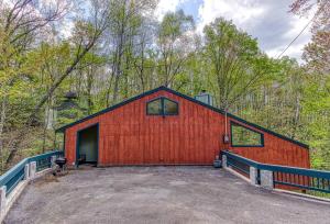 a red barn with a driveway in the woods at Peace, Serenity & Relaxation In The Smokies! in Gatlinburg
