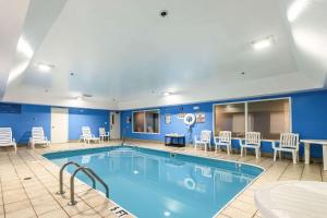 una piscina en una habitación de hotel con sillas y mesas en Comfort Inn & Suites en Dayton