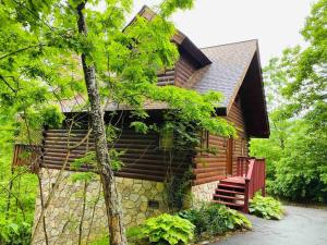 eine Blockhütte im Wald mit rotem Geländer in der Unterkunft Romantic, Honeymoon Cabin In The Smokies! in Gatlinburg