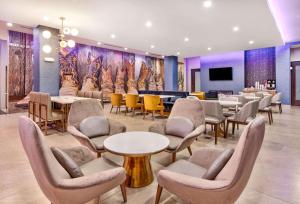 une salle d'attente avec des tables, des chaises et une télévision dans l'établissement La Quinta Inn & Suites by Wyndham Terrell, à Terrell