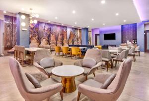 a waiting room with tables and chairs and a tv at La Quinta Inn & Suites by Wyndham Terrell in Terrell