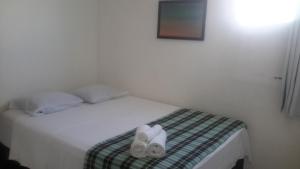 a white bed with two pairs of shoes on it at Pousada Mirante de Porto in Porto De Galinhas