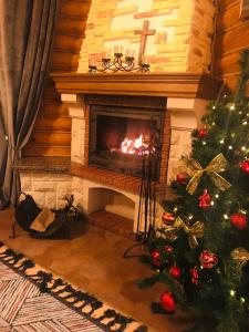 a christmas tree in a living room with a fireplace at Gostynnyi Dvir VIP HOUSE in Migovo