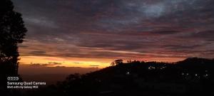 um pôr-do-sol no céu sobre uma montanha em Highcliffe Guest House em Haputale