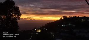 a sunset over a city with the sun setting at Highcliffe Guest House in Haputale