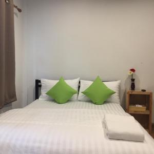 a bed with two green pillows on it at The Best House&Hostel in Ban Don Muang