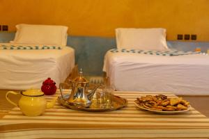 una mesa con una bandeja de comida en ella con dos camas en Dar Oussidi, en Merzouga