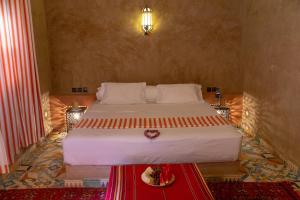 1 dormitorio con 1 cama grande y mesa roja en Dar Oussidi en Merzouga