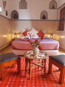 een slaapkamer met een bed met een tafel en 2 stoelen bij Riad Chalymar in Marrakesh