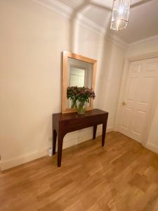 a room with a table with a mirror and flowers at Stylish Apartments in Victoria & Westminster in London