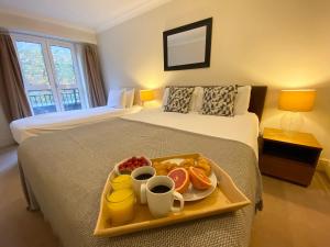 ロンドンにあるスタイリッシュ アパートメンツ イン ビクトリア ＆ ウェストミンスターのベッドに食料品のトレイを用意したホテルルーム