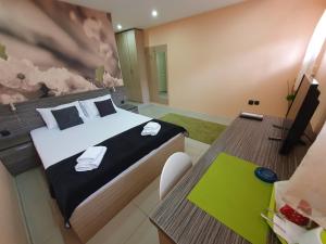 een slaapkamer met een bed en een bureau met een televisie bij Niš City Center Guest House in Niš