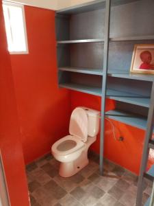 a bathroom with a toilet in a red wall at Maison Charlotte Forever Chambre d'hôtes chez un couple belgo togolais in Lomé