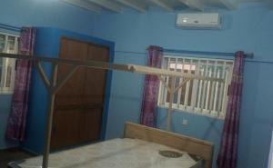 a room with a bed with a wooden stick at Maison Charlotte Forever Chambre d'hôtes chez un couple belgo togolais in Lomé