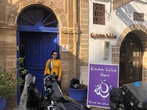 una mujer parada frente a un edificio con una moto en Casa Lila & Spa, en Essaouira