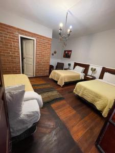 1 dormitorio con 2 camas y pared de ladrillo en Hotel Boutique Portal de Cantuña, en Quito