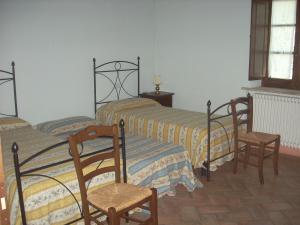1 dormitorio con 2 camas y 2 sillas en Agriturismo Il Pratone, en Castiglione dʼOrcia