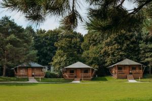 two cottages in a park with trees in the background at Glamping lodge with Eco-Wellness in Zeewolde