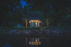 una piccola casa di notte con un riflesso nell'acqua di เมี่ยงไม้ รีสอร์ท a Ban Khlong Khen