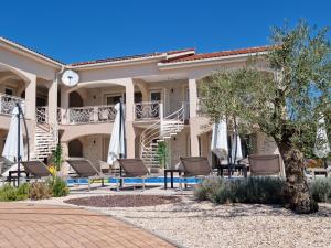 a patio with chairs and umbrellas in front of a building at Villa Luka Lopar in Lopar