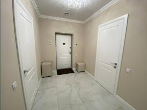 un corridoio vuoto con due porte bianche e un pavimento piastrellato bianco di Lux 1-bedroom panoramic view Most City Center area a Dnipro