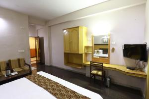 Habitación de hotel con cama y TV en Hotel Mayas, en Tiruchchirāppalli