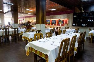 a dining room with tables and chairs with white tablecloths at Hotel Tulipa in Bragança