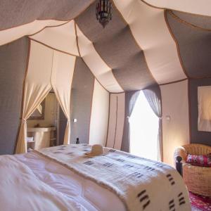 a bedroom with a bed with a comforter on it at Sahara Tours luxury camp in Merzouga