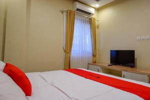 a bedroom with a white bed and a television at RedDoorz near MM UGM in Yogyakarta