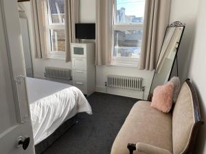 a bedroom with a bed and a chair and two windows at Cosy 2 Bedroom House -2022 & 2023 Award Winner! in Ramsgate