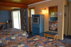 a hotel room with two beds and a television at Auberge Godard in Nominingue