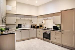 a large kitchen with white cabinets and appliances at 3 Bedroom City Centre Townhouse in Nottingham