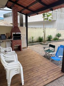 a patio with white chairs and a grill at Casa para temporada in Governador Celso Ramos