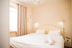una camera da letto con un letto bianco con lenzuola e cuscini bianchi di Desert View a Yeroẖam