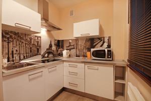 cocina con armarios blancos y microondas en ApartSerwis - Apartament Paryski, en Zakopane