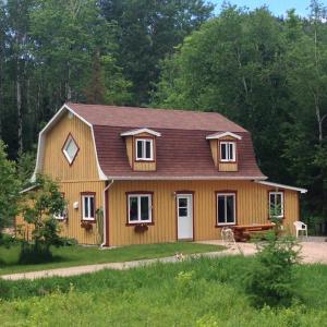 a wooden house with a gambrel roof at Grangette Entre Chiens et Loups in LʼAnse-Saint-Jean