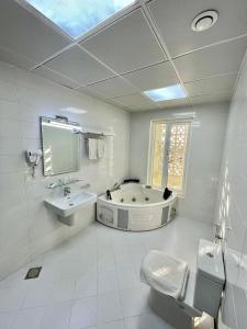 a bathroom with a tub and a toilet and a sink at A'Sinamar Hotel Apartment in Muscat